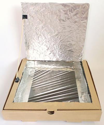 A cardboard pizza box with a flap cut in the top.  The box is lined with tin foil and the opening created by the flap is covered with clear plastic wrap.