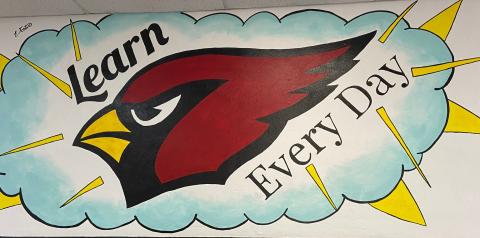 A wall mural of a the head of a cardinal (red bird) inside a cloud.  The cloud is surrounded by lightning bolts.  The motto "Learn Every Day" surrounds the bird's head