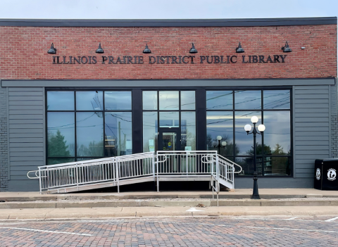 A one-story building with a brick and glass façade.  Stairs and a wheelchair ramp lead up to the front door.