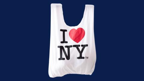 A white tote bag on a navy blue background.  The tote bag has "I (heart emoji) NY" on it