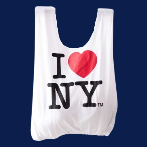 A white tote bag on a navy blue background.  The tote bag has "I (heart emoji) NY" on it.