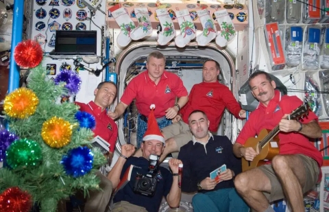 A group of astronauts on the International Space Station pose for a holiday photo near an improvised Christmas tree.