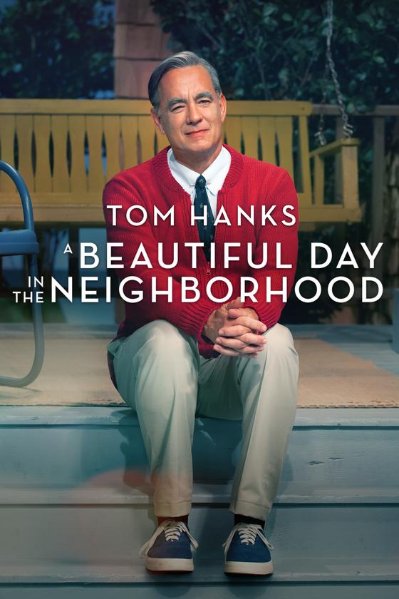 Tom Hanks dressed as Mr. Rogers, sitting on the steps of a front porch.