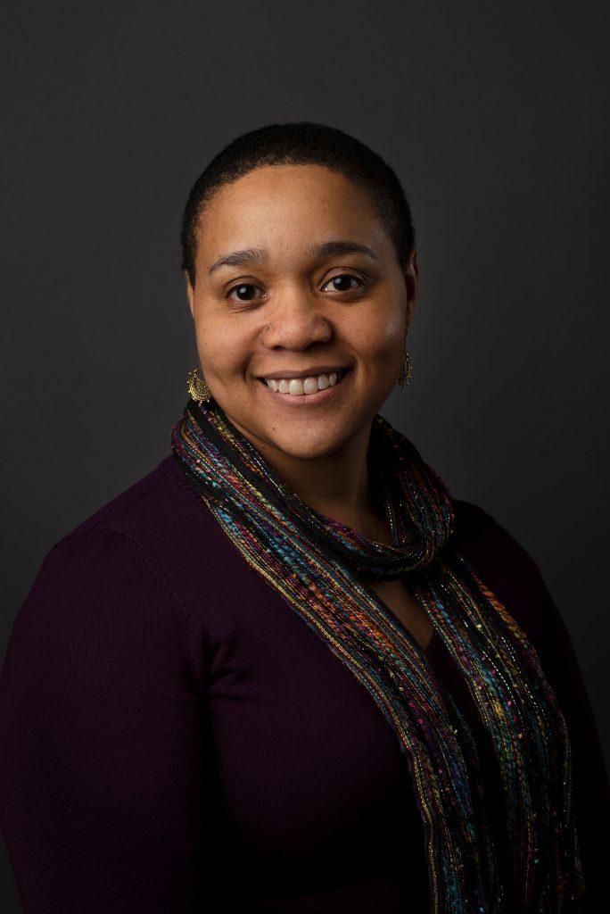 A smiling dark-skinned woman with short hair