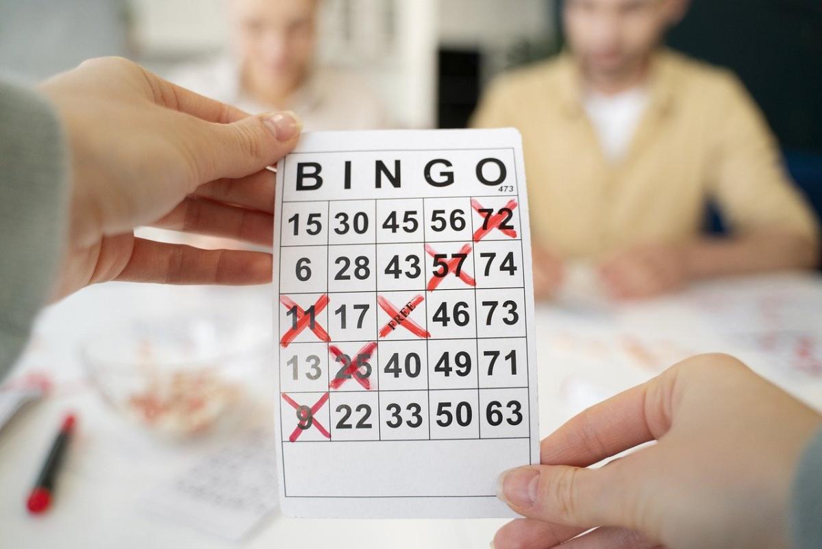 A person holding a BINGO card with two others in the background.